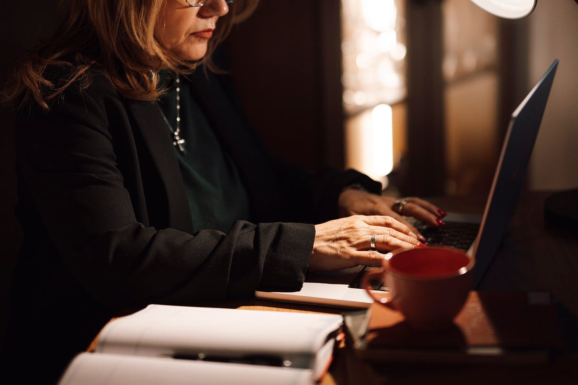 A businesswoman typing on a laptop at a home desk